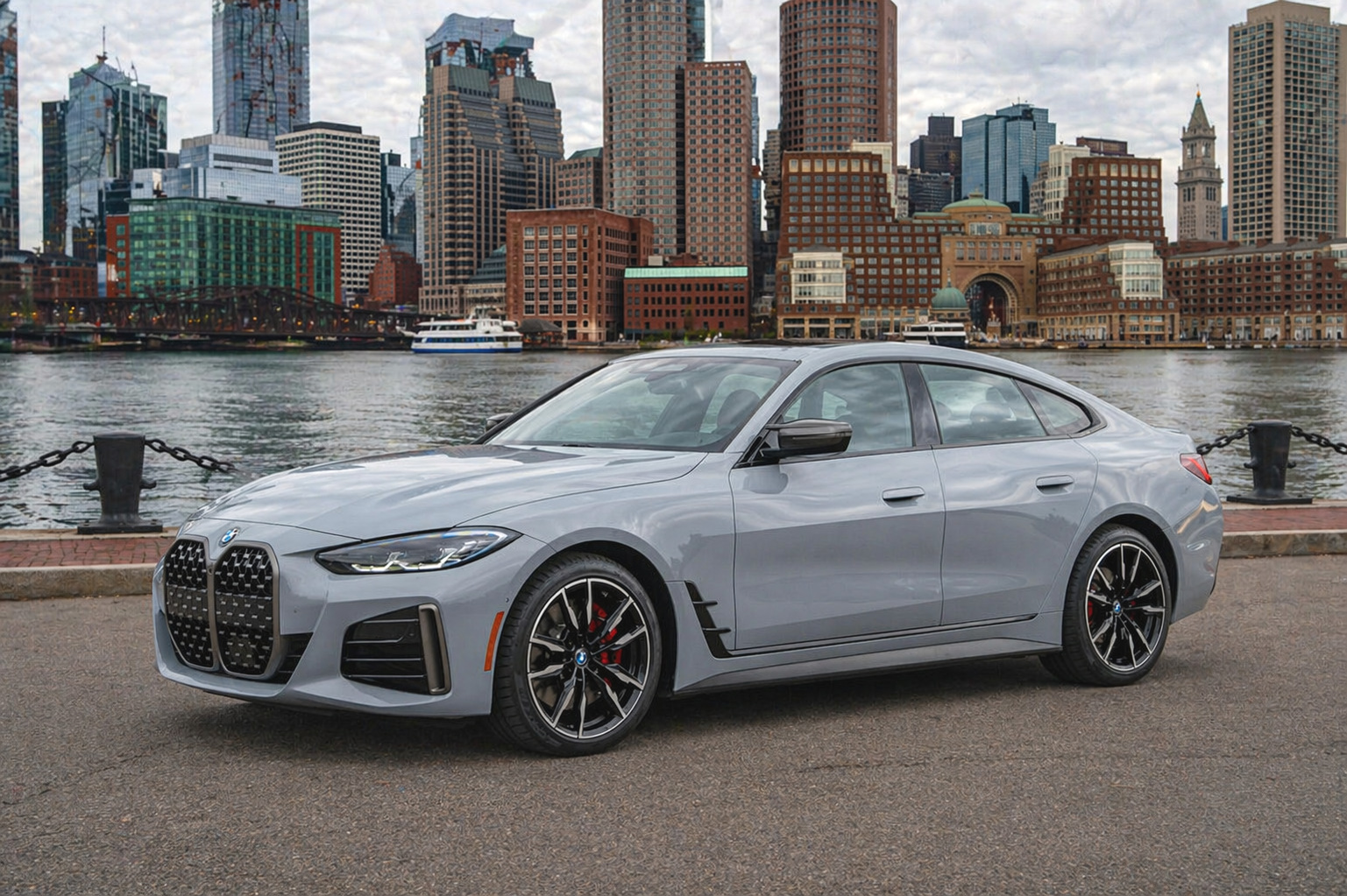 Gray BMW sedan parked by water, overcast sky.