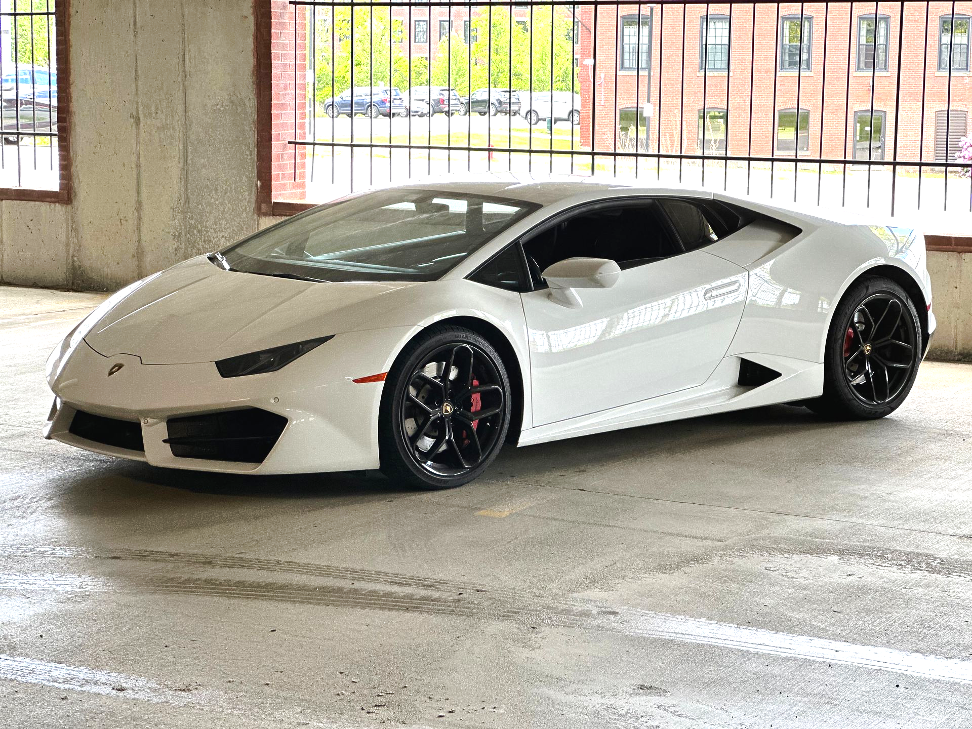 White Lamborghini sports car parked in front of a building with glass windows.