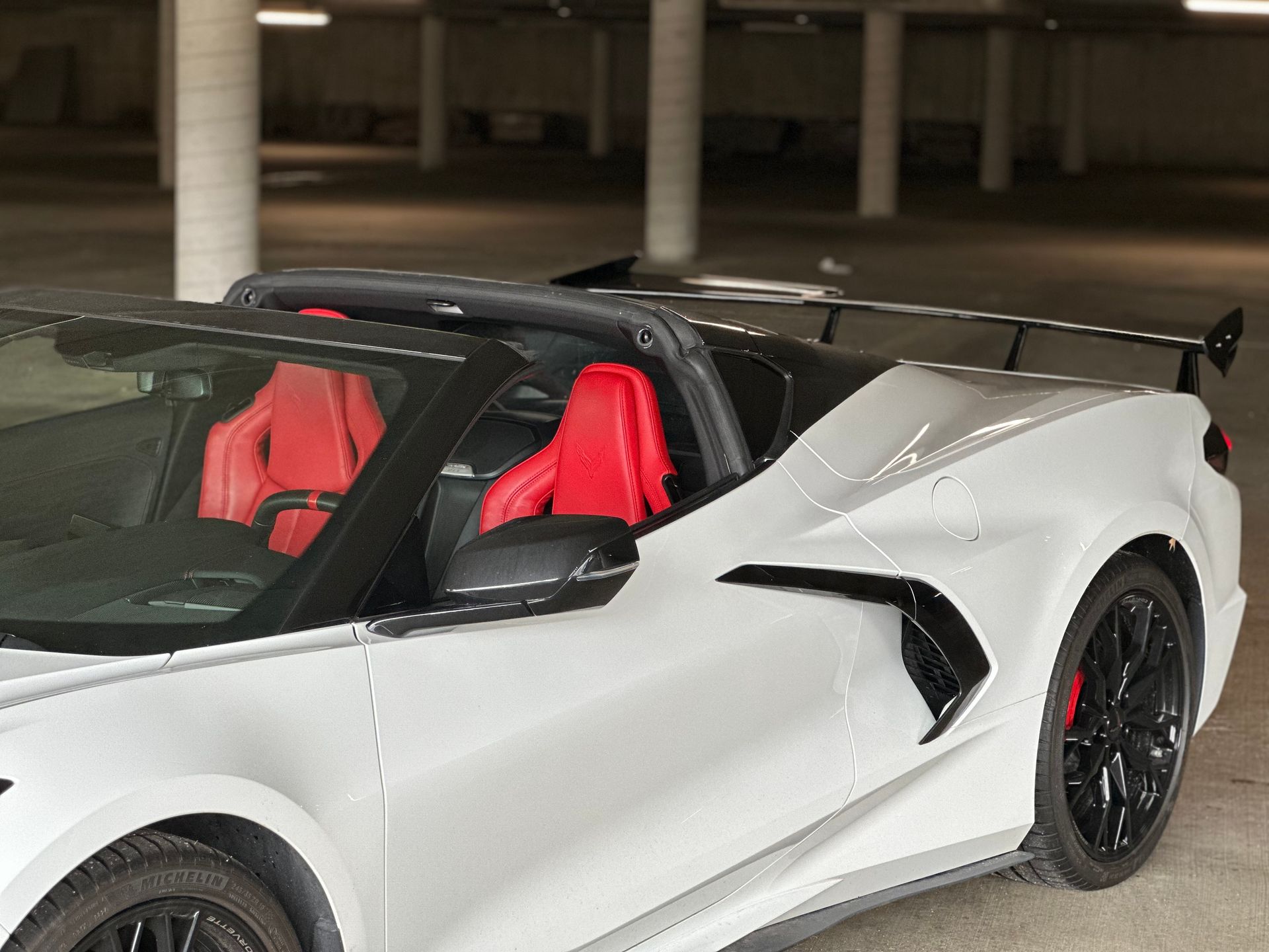 White sports car with red seats parked in a dim garage