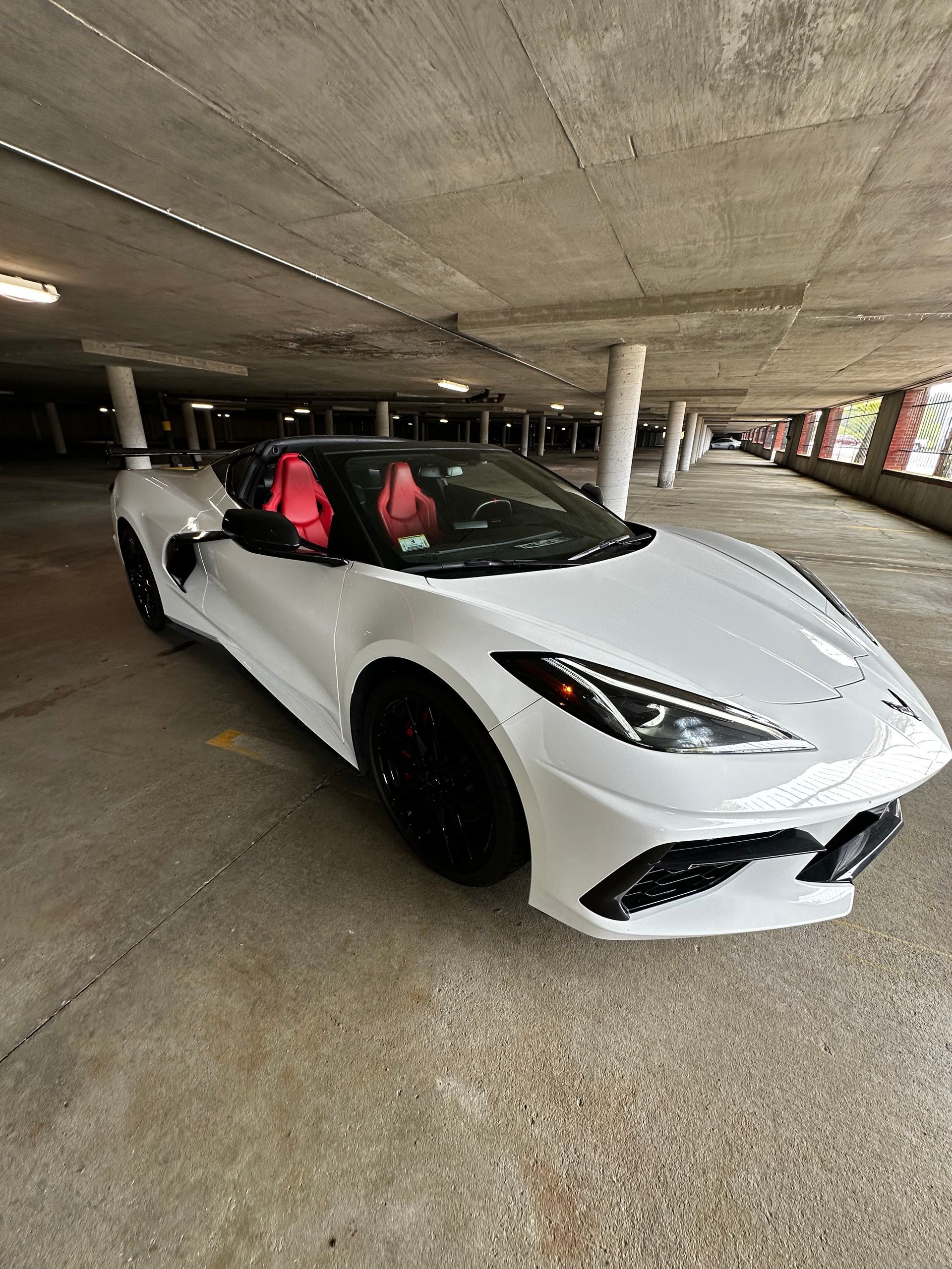 White sports car with red seats parked in a concrete garage