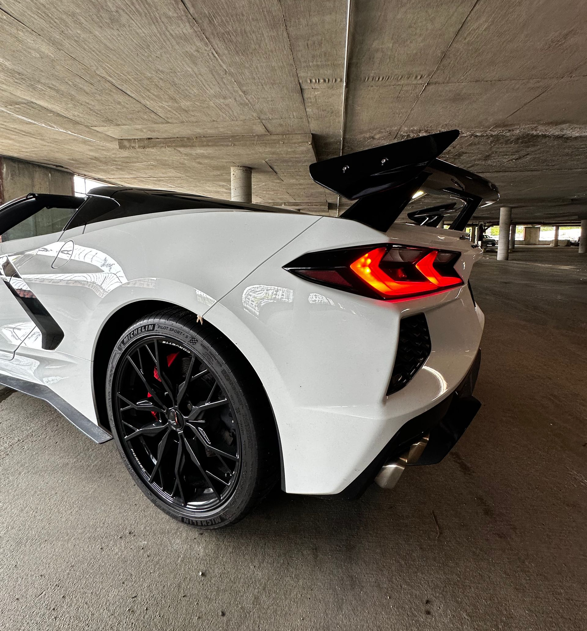 White sports car with black wheels and red taillights parked in a concrete garage