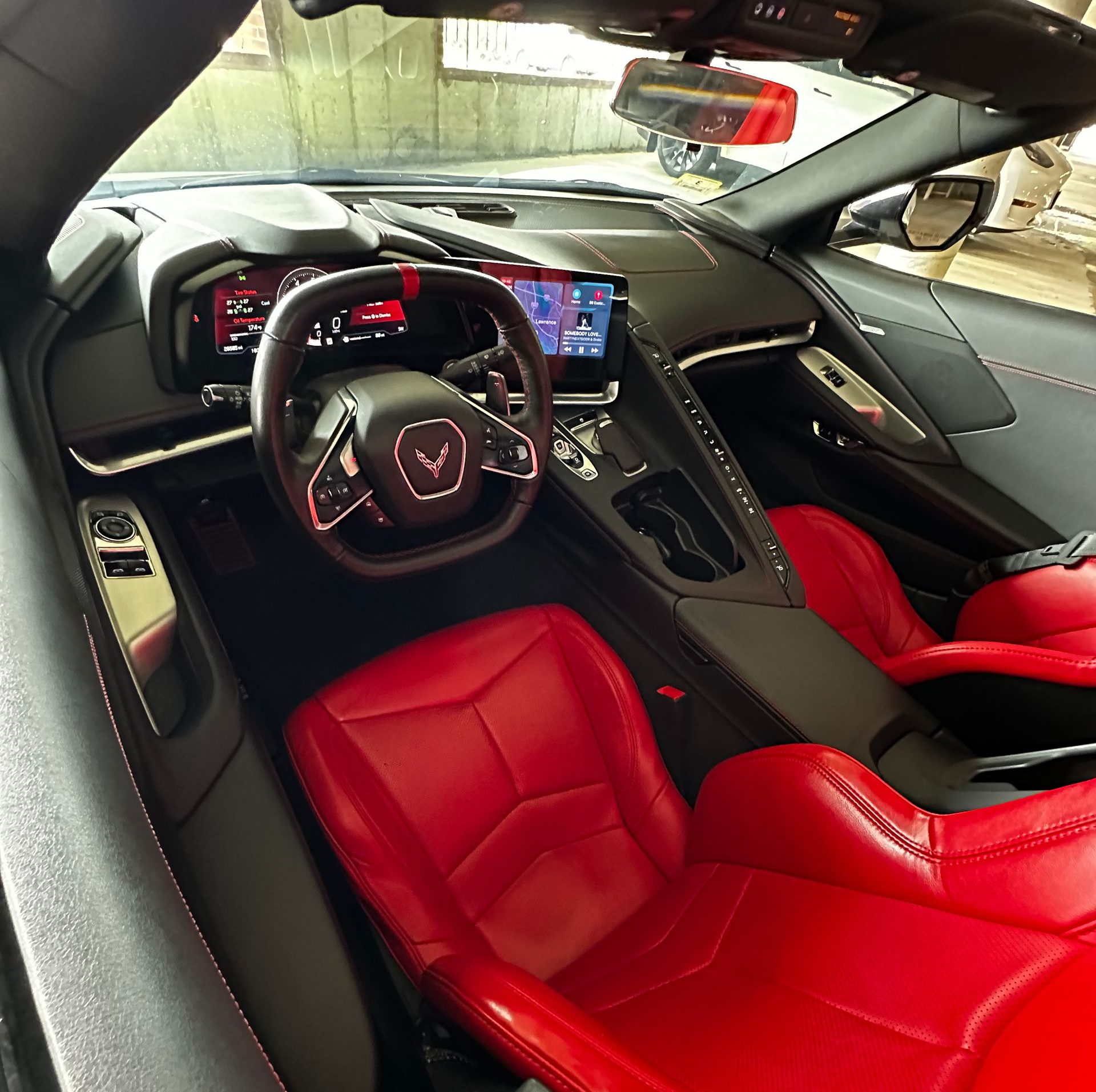 Red leather sports car interior with steering wheel, digital dashboard, and center console.