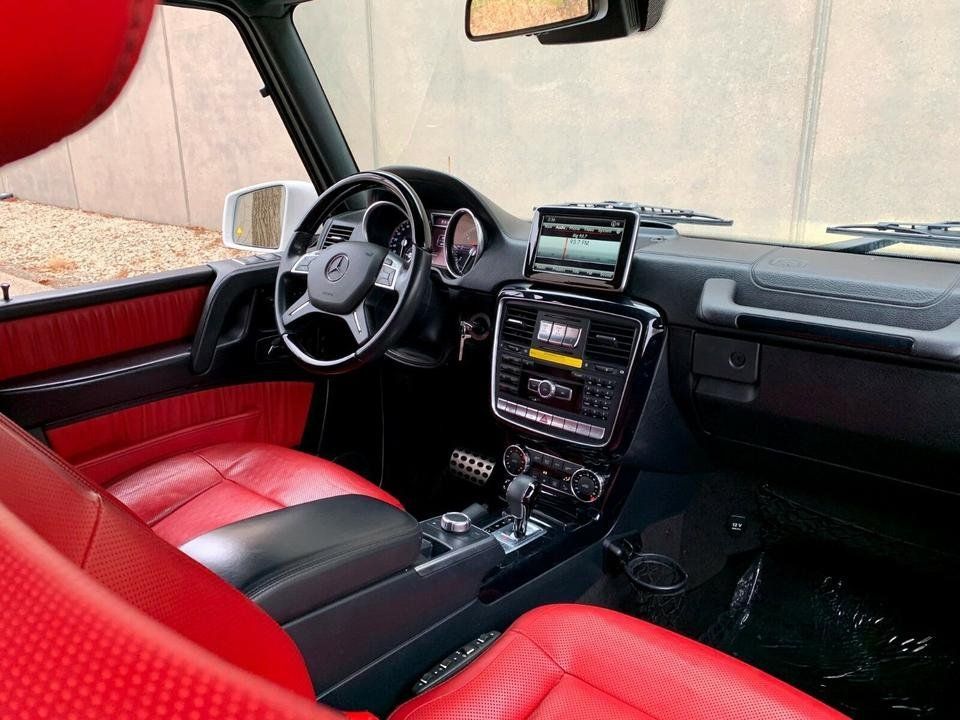 Red-and-black car interior with steering wheel, dashboard screen, and center console view