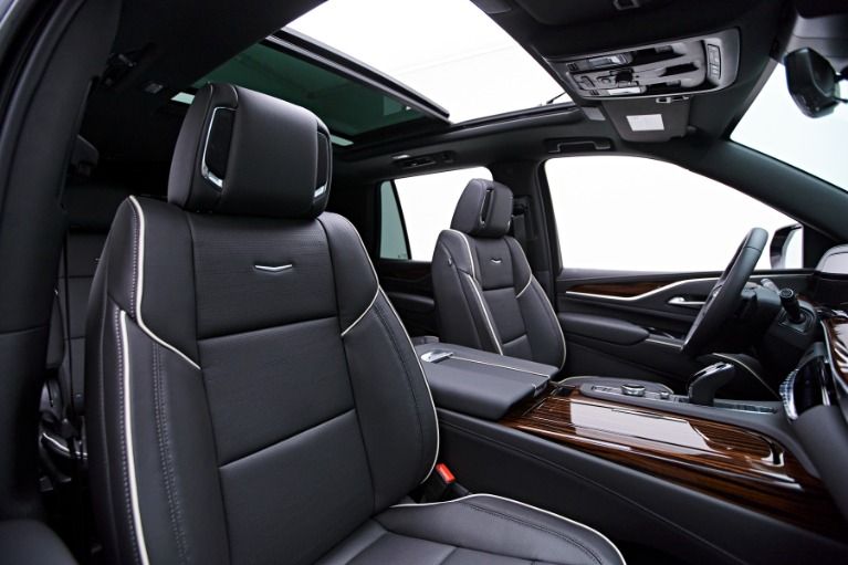 Luxury car interior with black leather seats, wood trim, and a panoramic sunroof.