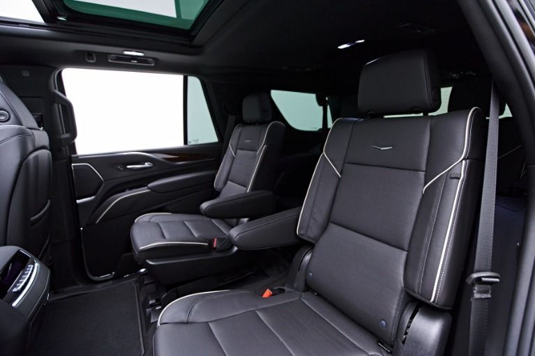 Luxury car interior with black leather seats and a sunroof, viewed from the back seat