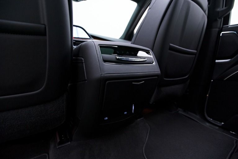 Dark car back seat with center console, vents, and cupholders in a black interior