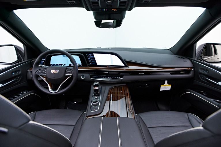 Luxury car interior with black leather seats, wood trim, and panoramic glass roof