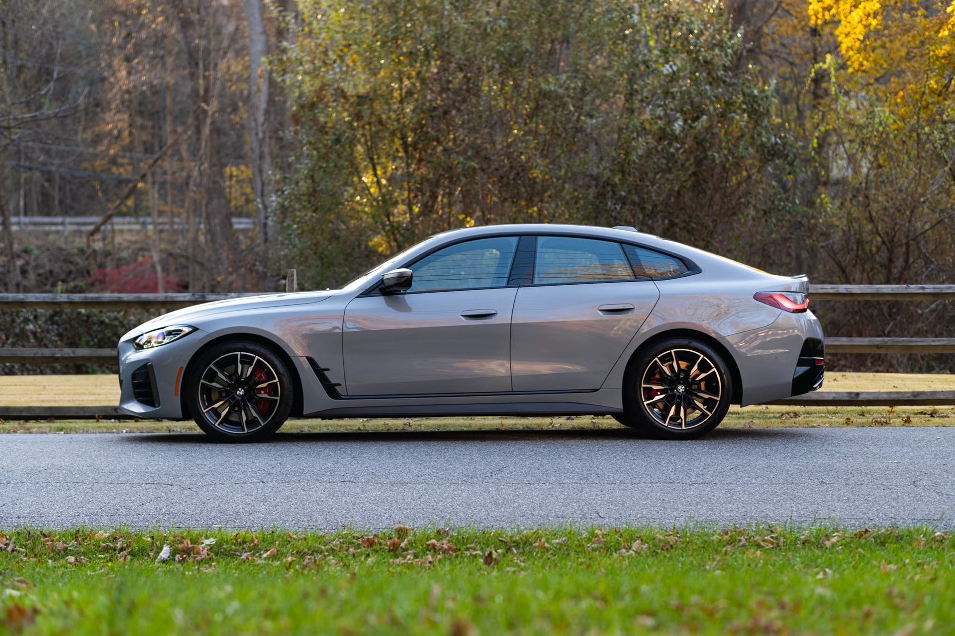 Silver sedan parked on a roadside with autumn trees in the background