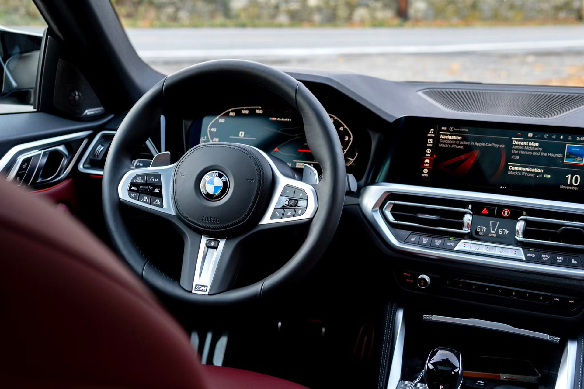 BMW car interior with digital dashboard, steering wheel, and center console in black and red trim