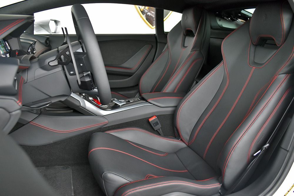 Luxury sports car interior with black leather seats, red stitching, and center console