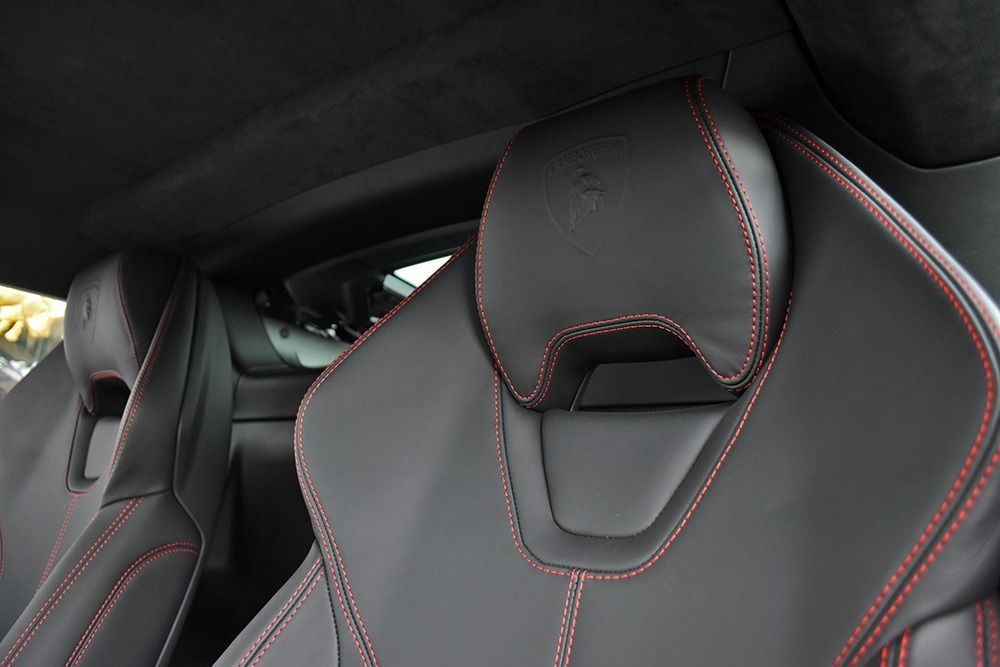Black leather car racing seats with red stitching in a vehicle interior