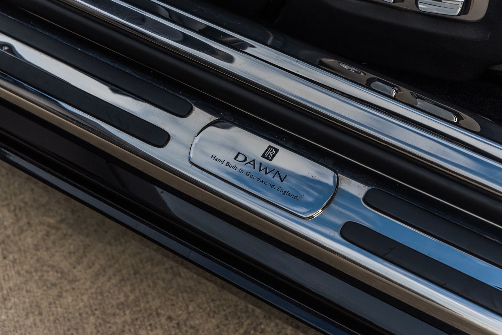 Shiny metal Rolls-Royce Dawn door sill with logo and model name.