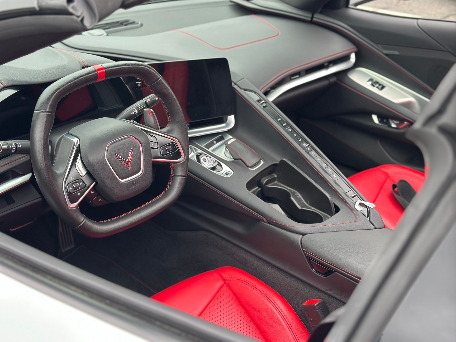 Luxury sports car interior with black trim and red seats, showing the steering wheel and center console.