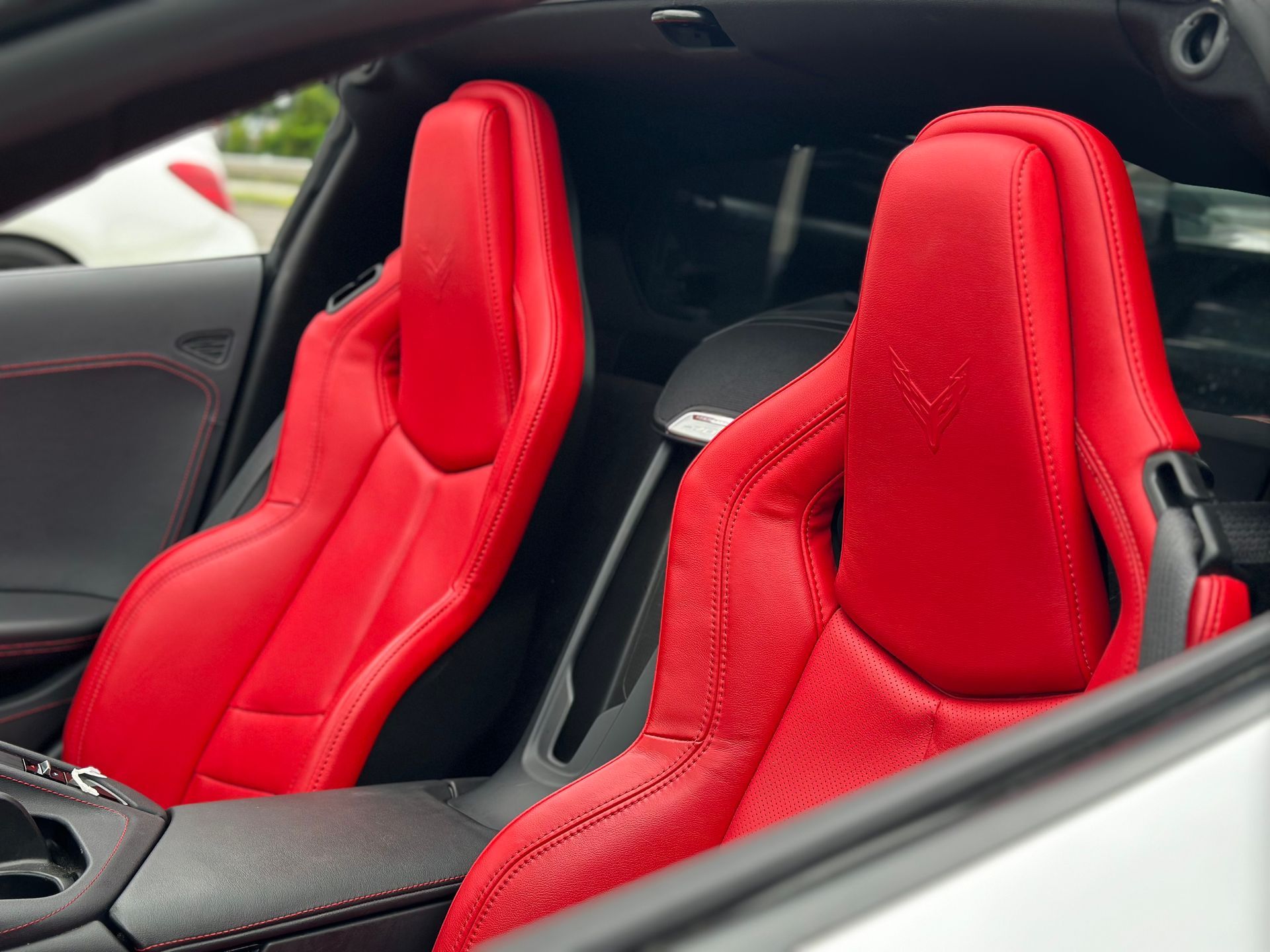 Interior of a sports car with two bright red racing seats and black trim, viewed from the side