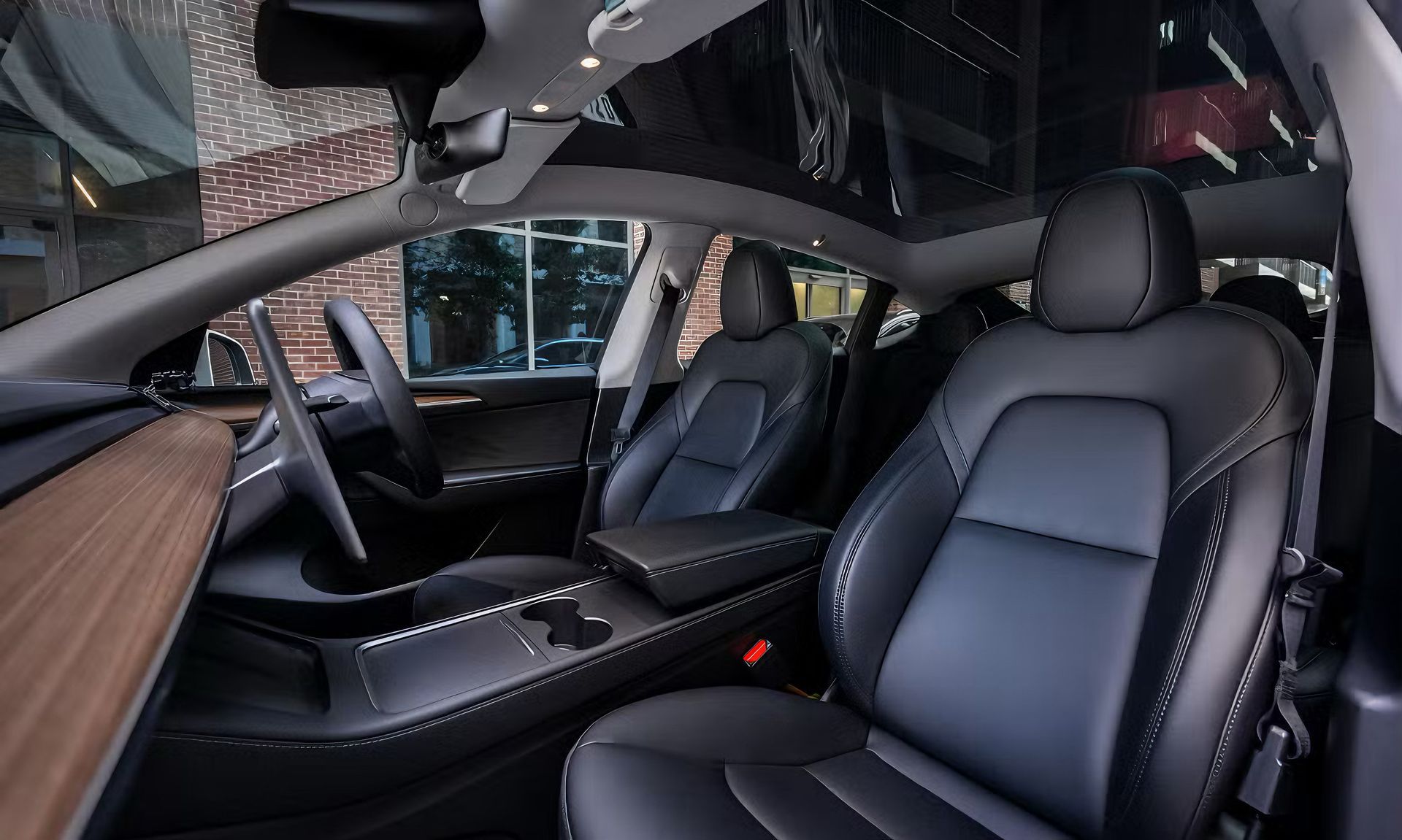 Luxury car interior with black leather seats, panoramic roof, and visible red seatbelt buckle