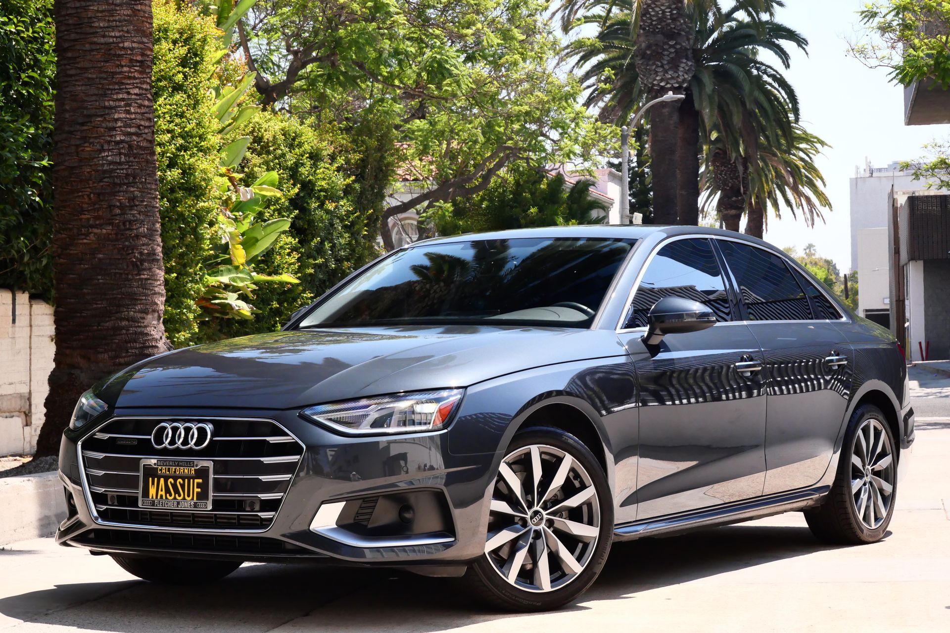 Gray Audi sedan parked outdoors near palm trees.
