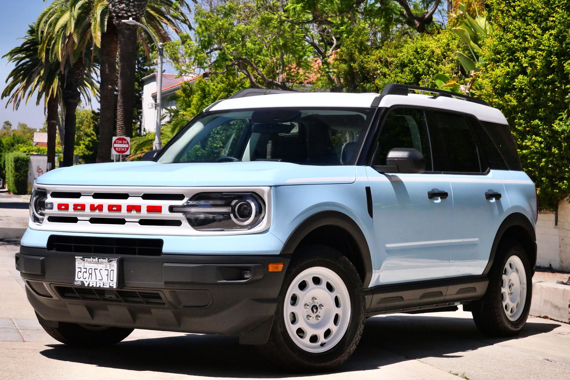 Light blue Ford Bronco Sport SUV with white roof and wheels, parked on a city street.
