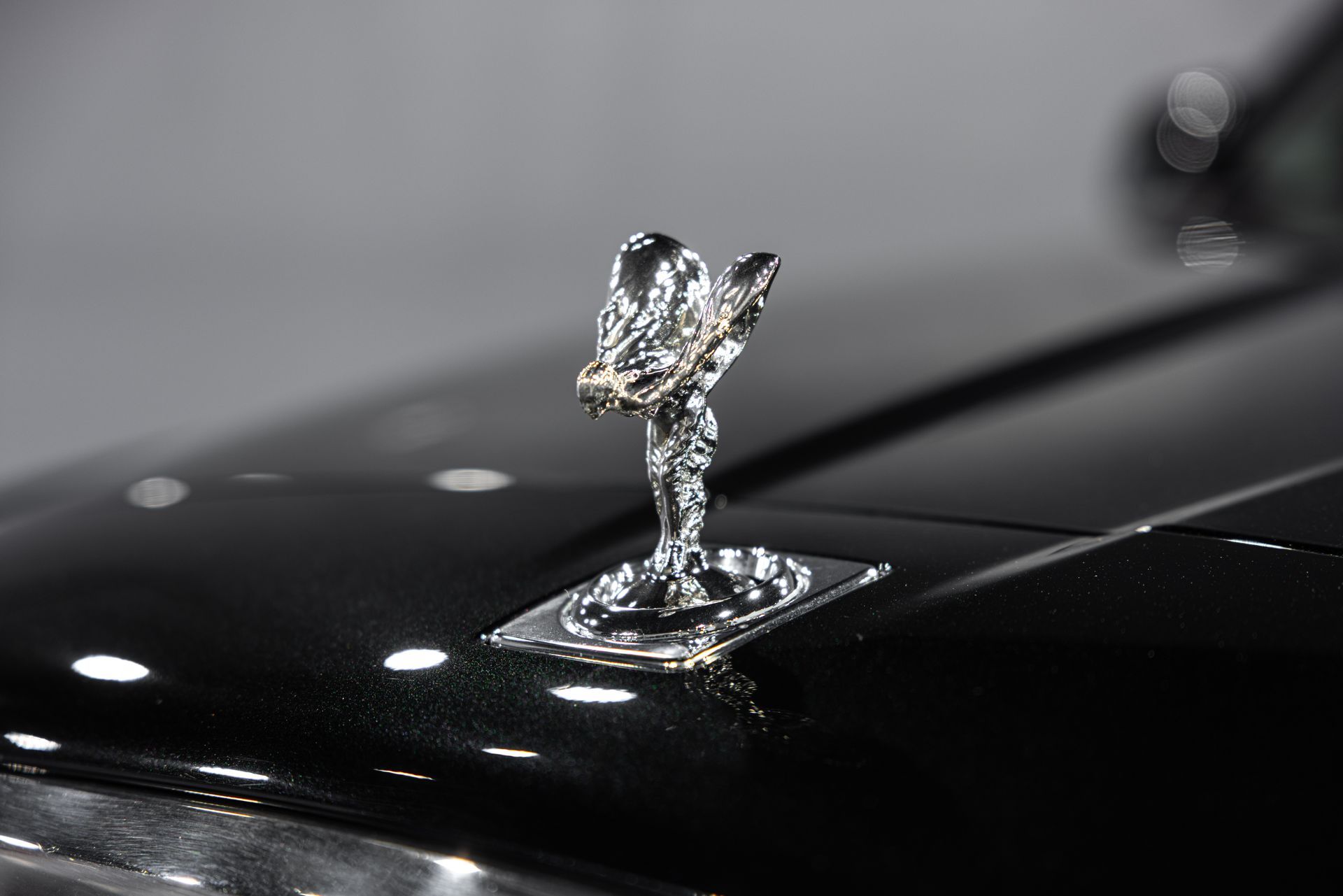 Chrome Rolls-Royce hood ornament on a glossy black car hood