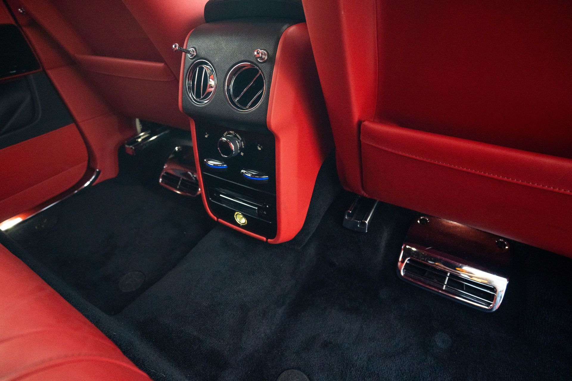 Red car interior with black floor mats, center console, and chrome pedals