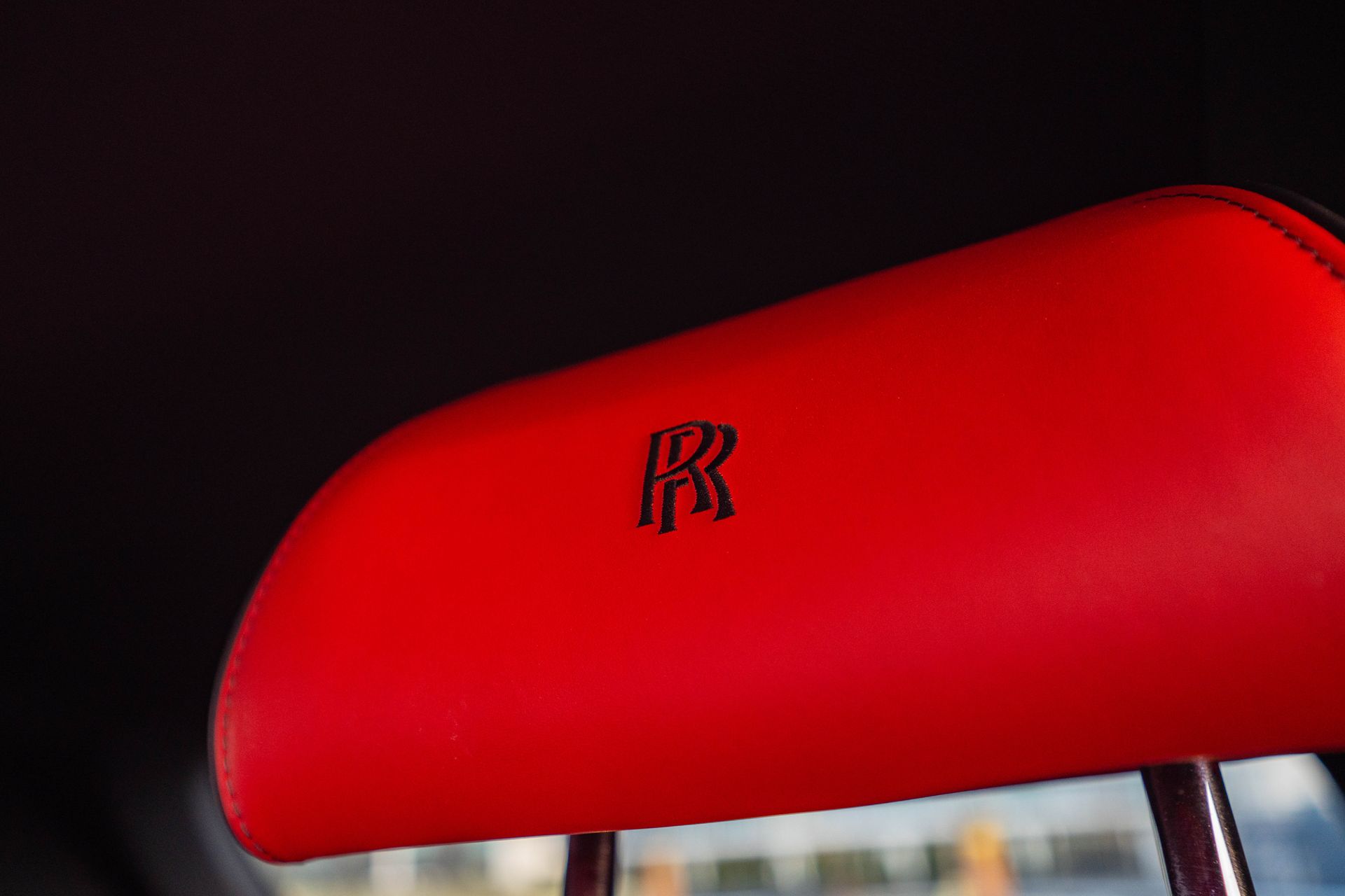 Red car headrest with Rolls-Royce logo on a dark background