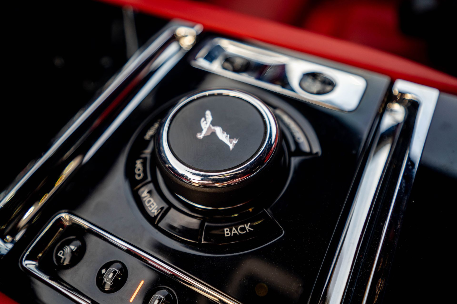 Close-up of a luxury car center console with glossy black controls and a large rotary dial