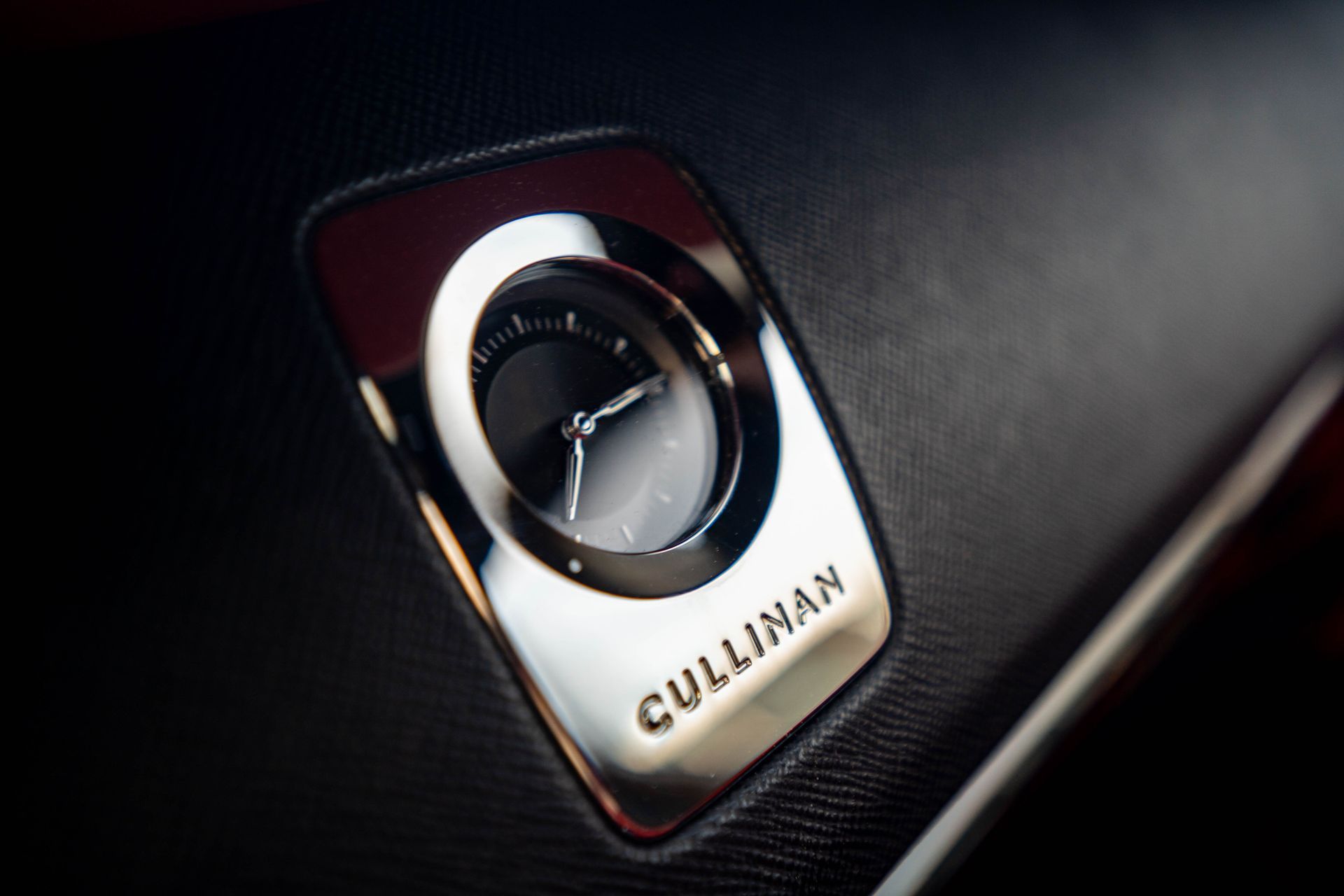 Close-up of a Rolls-Royce Cullinan dashboard badge and air vent in black and silver.