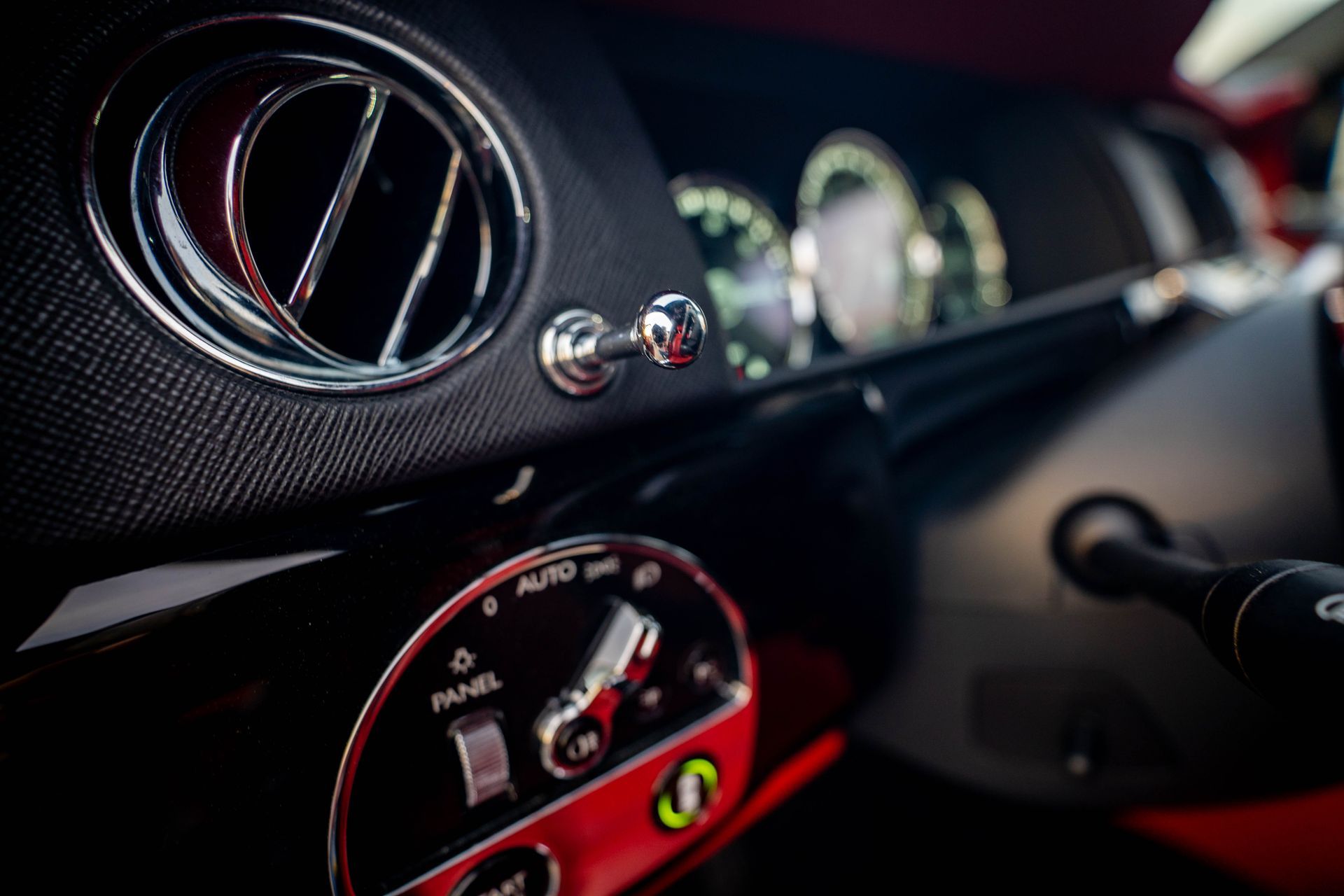 Close-up of a car dashboard with chrome vents, dials, and red accents