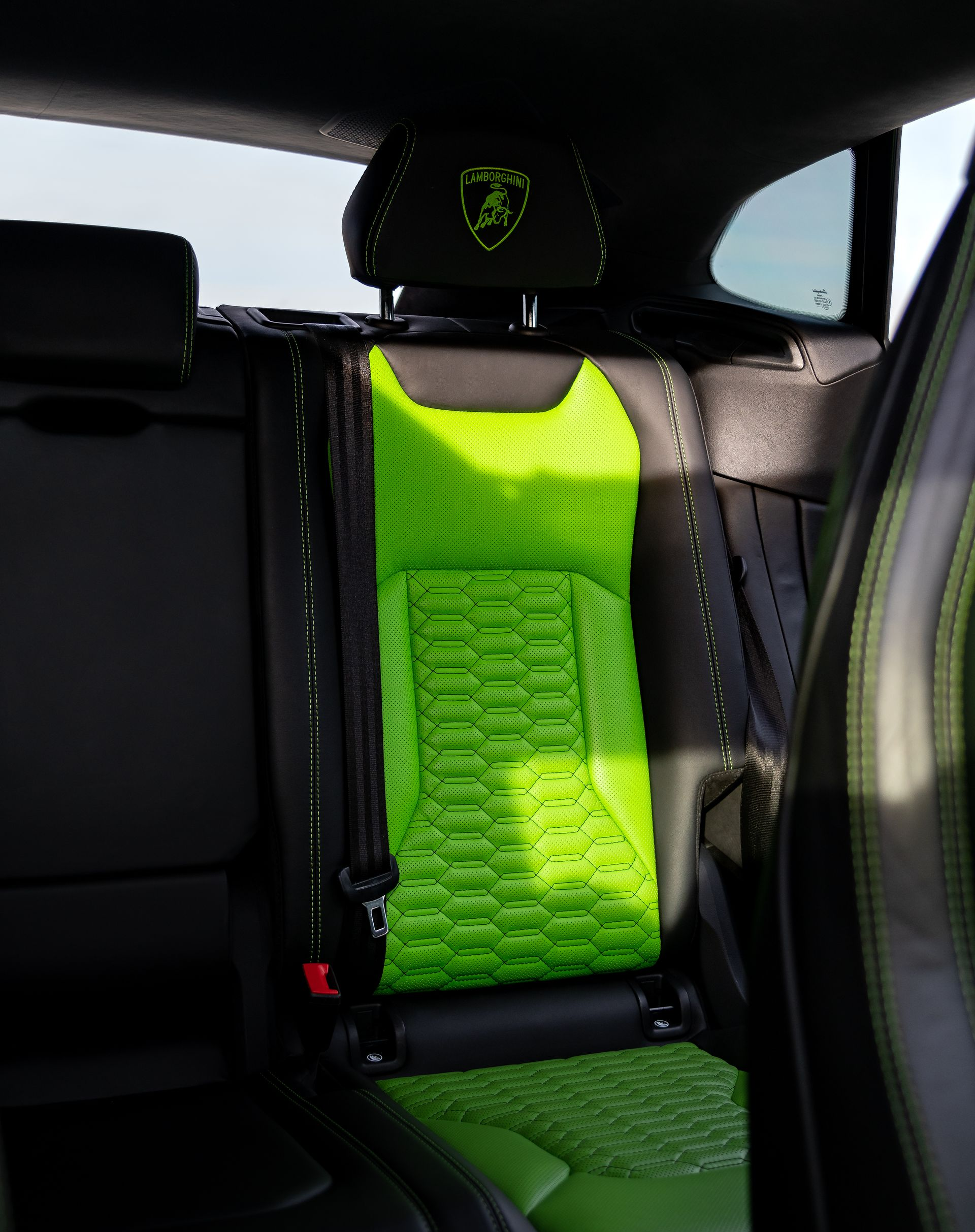 Neon green car seat cover installed on a rear seat inside a vehicle.