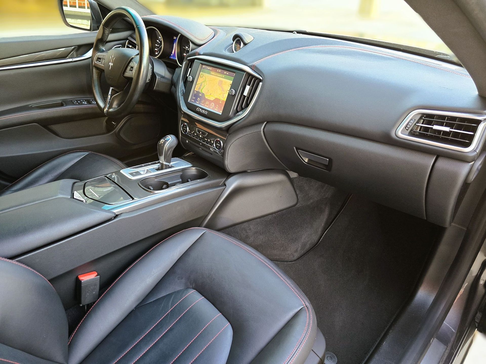 Car interior with black leather seats, center console, and dashboard touchscreen display