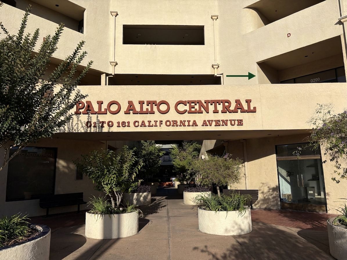 Entrance sign for Palo Alto Central, with beige apartment building and trees in the foreground