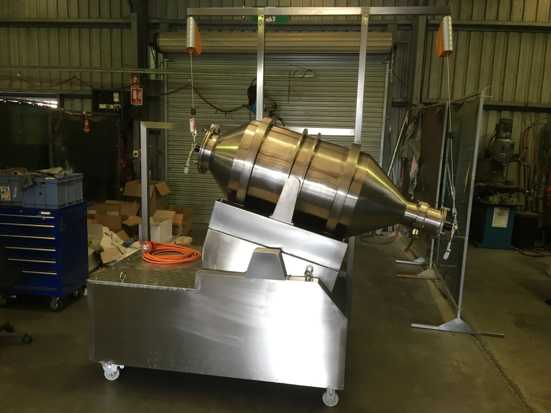 A large stainless steel machine is sitting on a cart in a warehouse. — Keystone Engineering Sheet Metal Industries in Noosaville, QLD