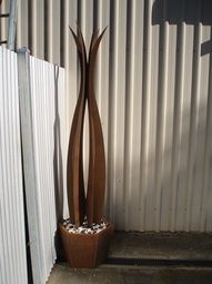 A large metal sculpture is sitting in a pot next to a white wall. — Keystone Engineering Sheet Metal Industries in Noosaville, QLD