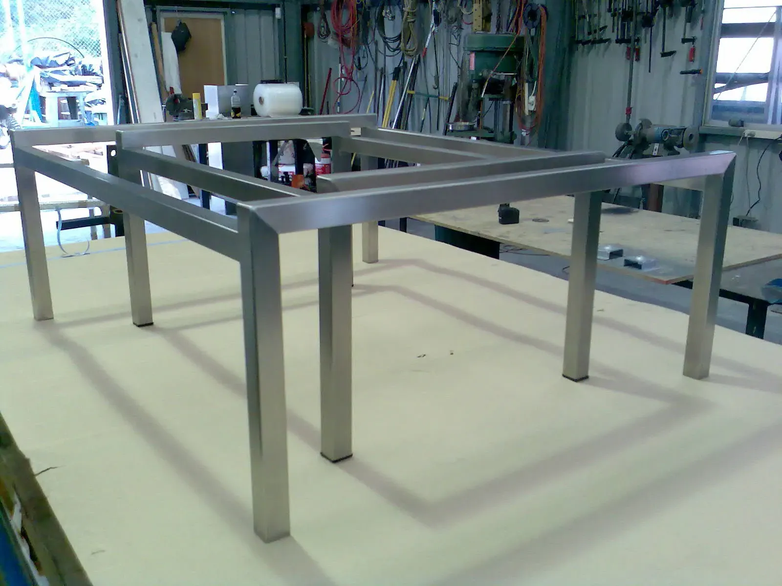 A stainless steel table frame is sitting on a wooden table in a workshop. — Keystone Engineering Sheet Metal Industries in Noosaville, QLD