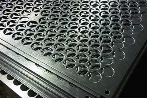A stack of perforated metal sheets sitting on top of each other on a table.