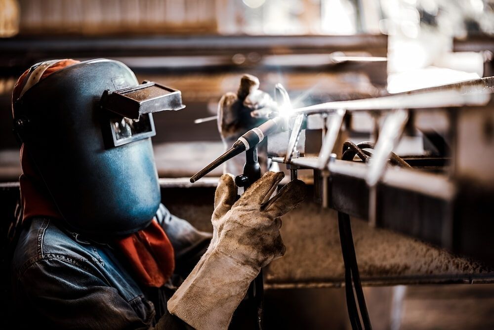 A Man Is Welding A Piece Of Metal In A Factory — Keystone Engineering Sheet Metal Industries in Noosaville, QLD