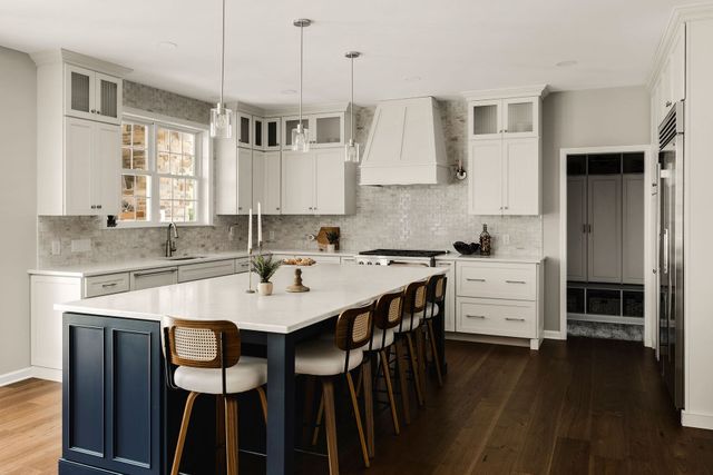 Bright modern kitchen with white cabinets, dark island, and four bar stools