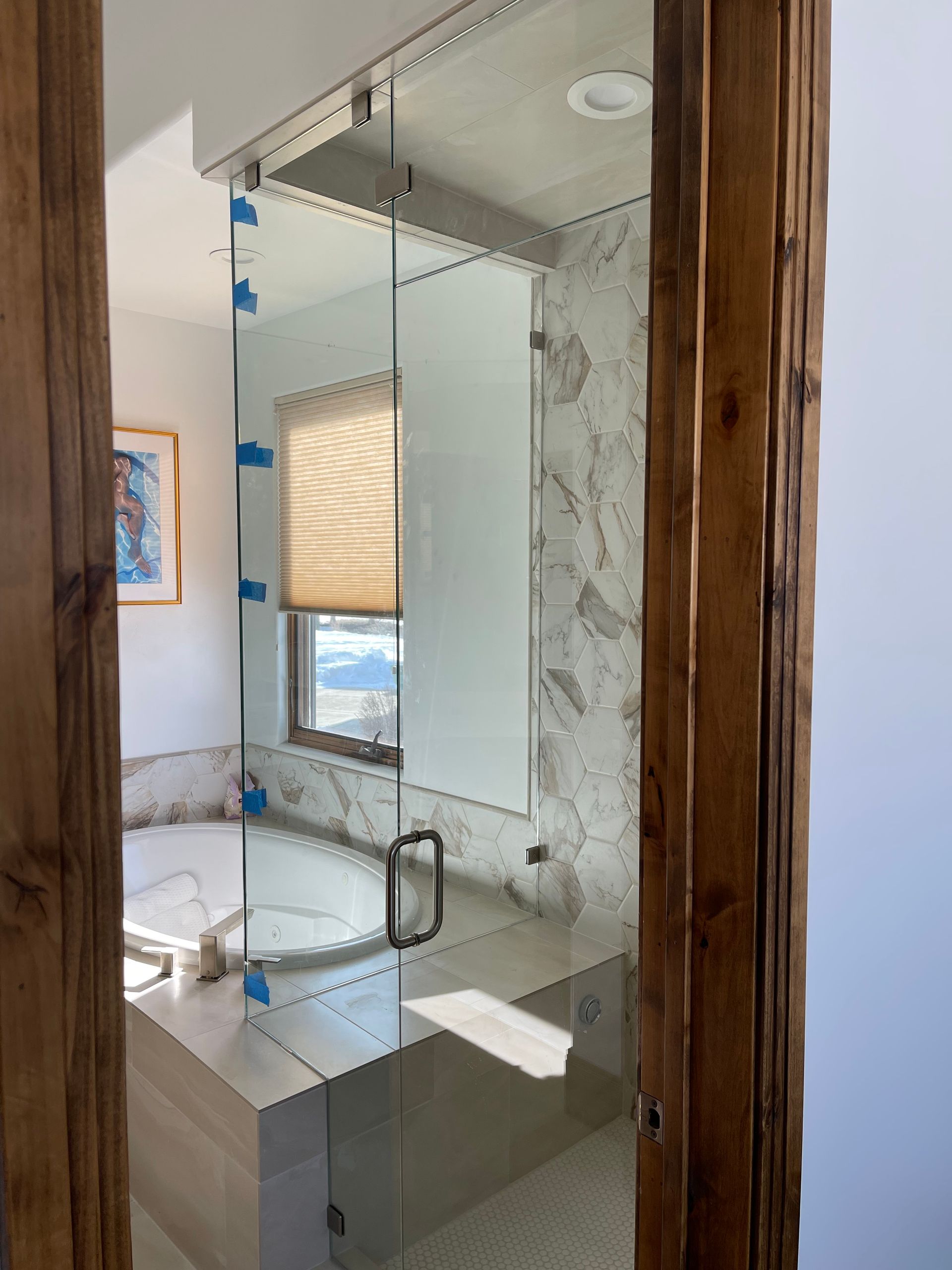 Glass shower enclosure with a wooden door frame, bathroom setting.