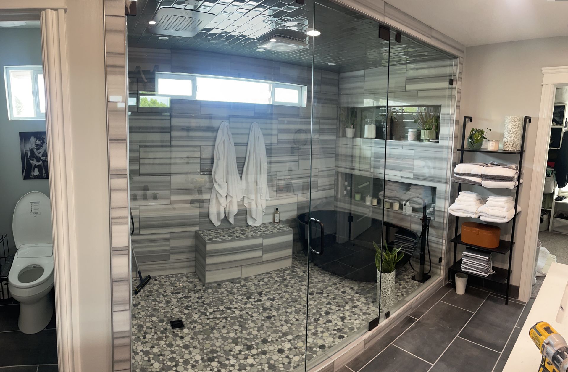 Bathroom with glass shower, pebble floor, and towel rack; toilet visible on the left.