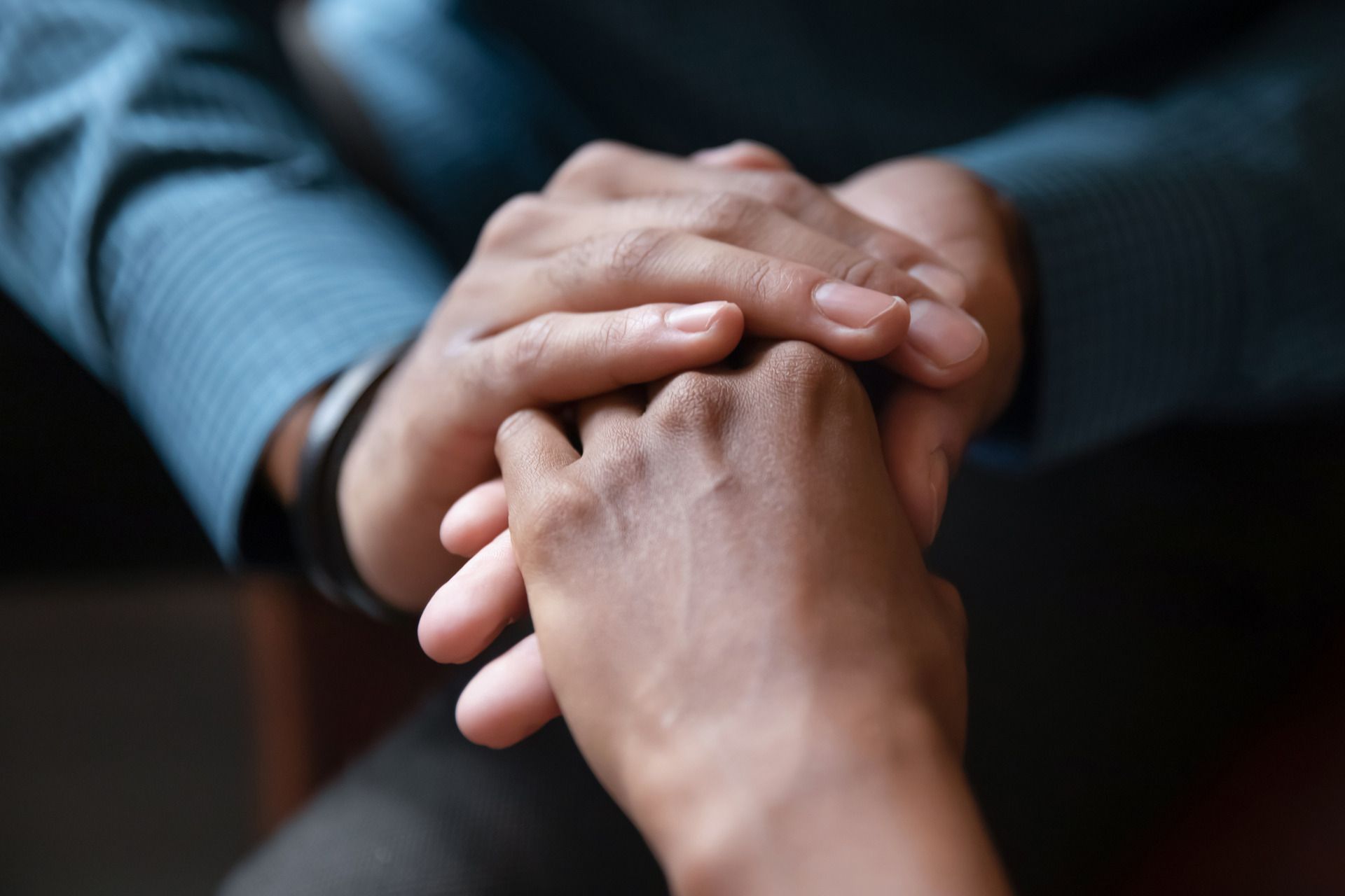 A man and a woman are holding hands against a tree trunk.