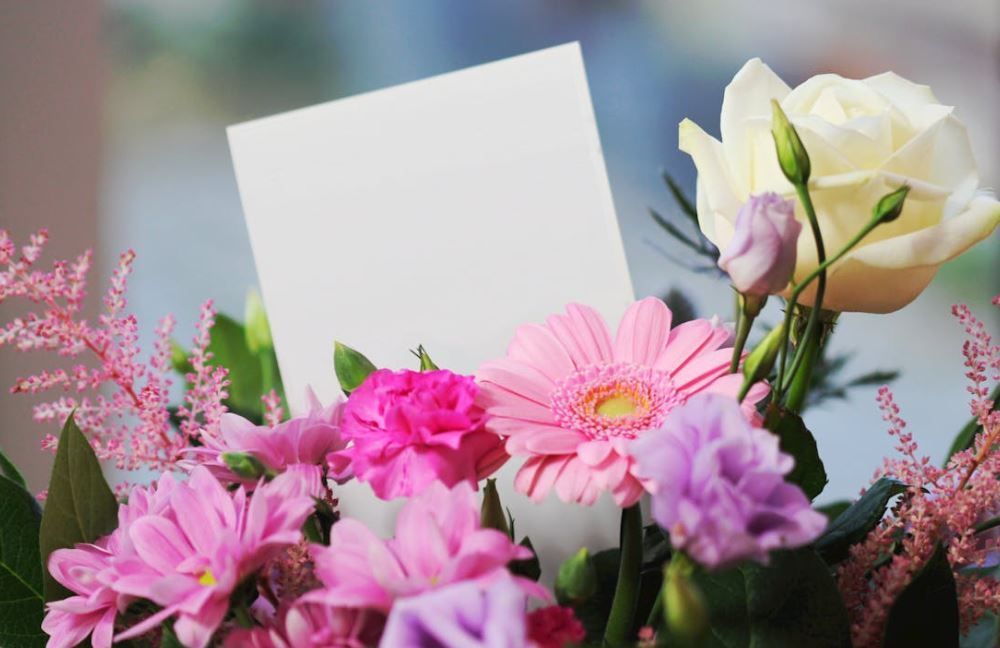 Pink gerbera and white rose bouquet with empty note card for a personal tribute, cremation services Westminster, MD