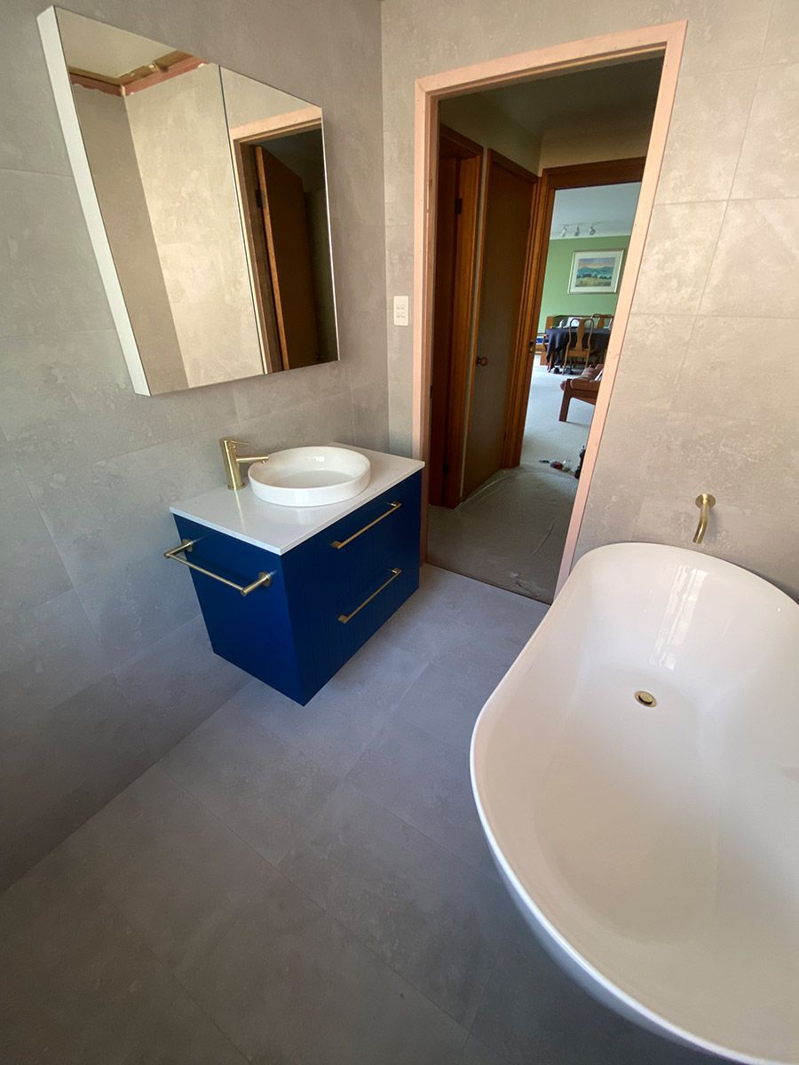 A Bathroom With A Bathtub , Sink And Mirror — B Smart Building & Design In Figtree, NSW