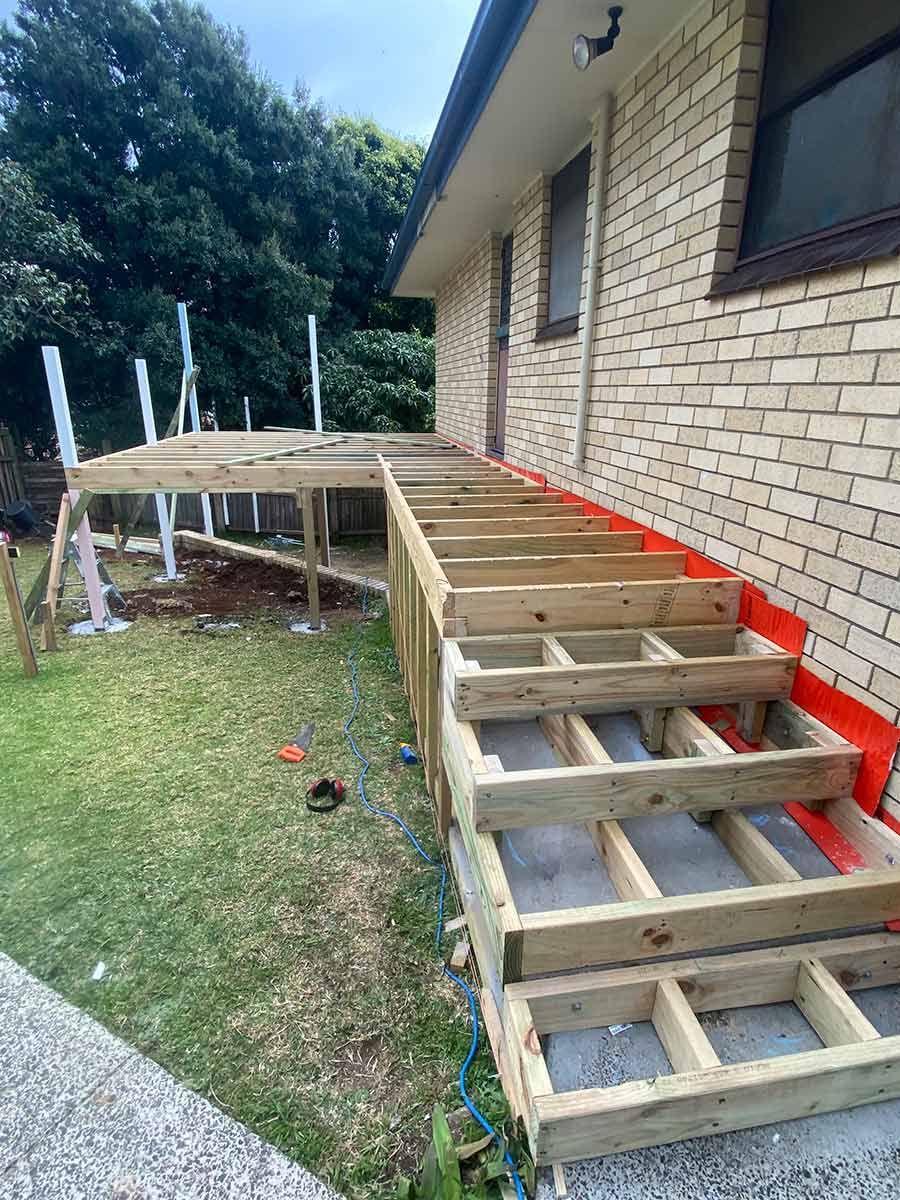 A Wooden Deck Is Being Built On The Side Of A Brick House — B Smart Building & Design In Figtree, NSW