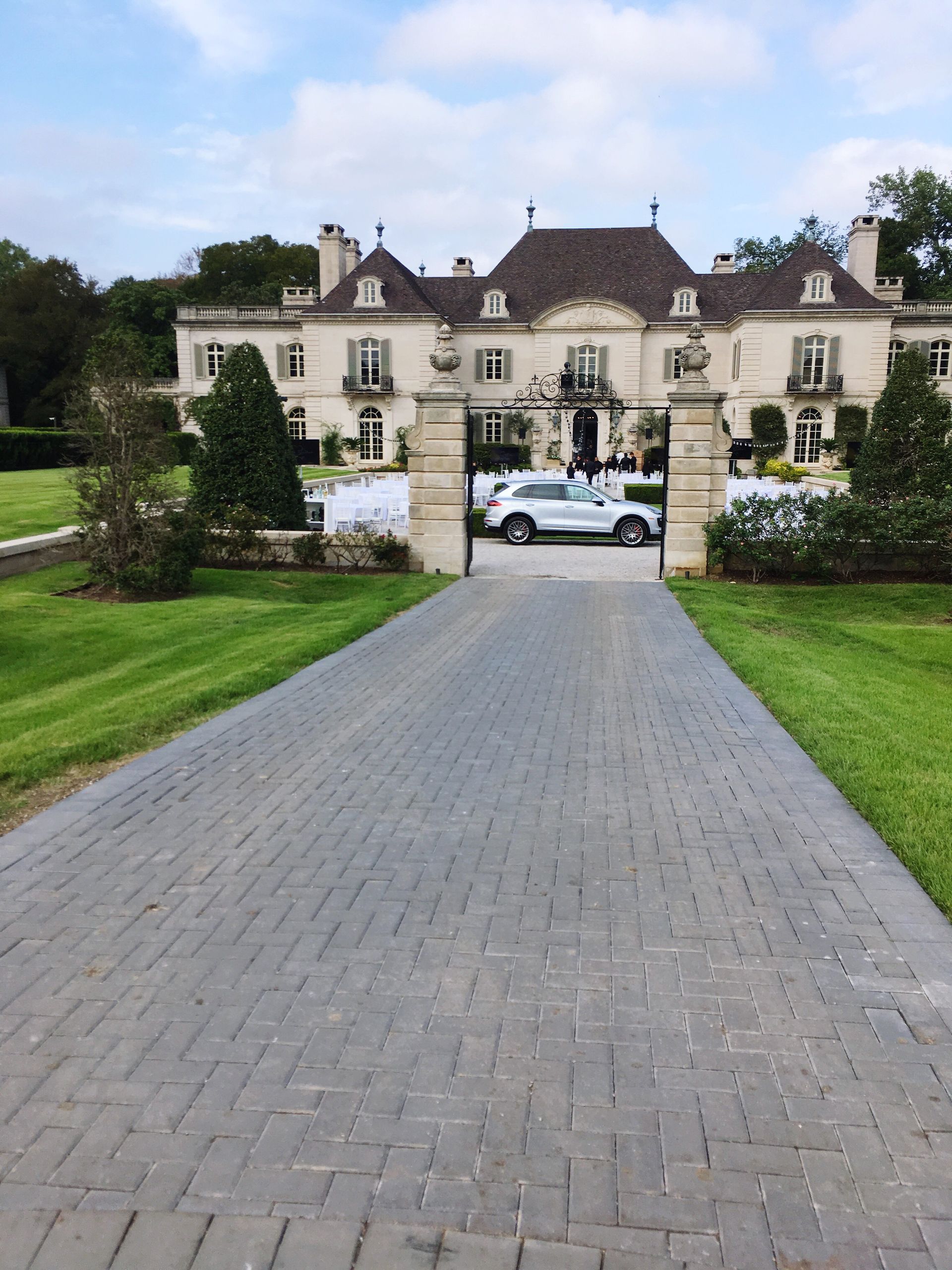 A brick driveway leading to a large white house