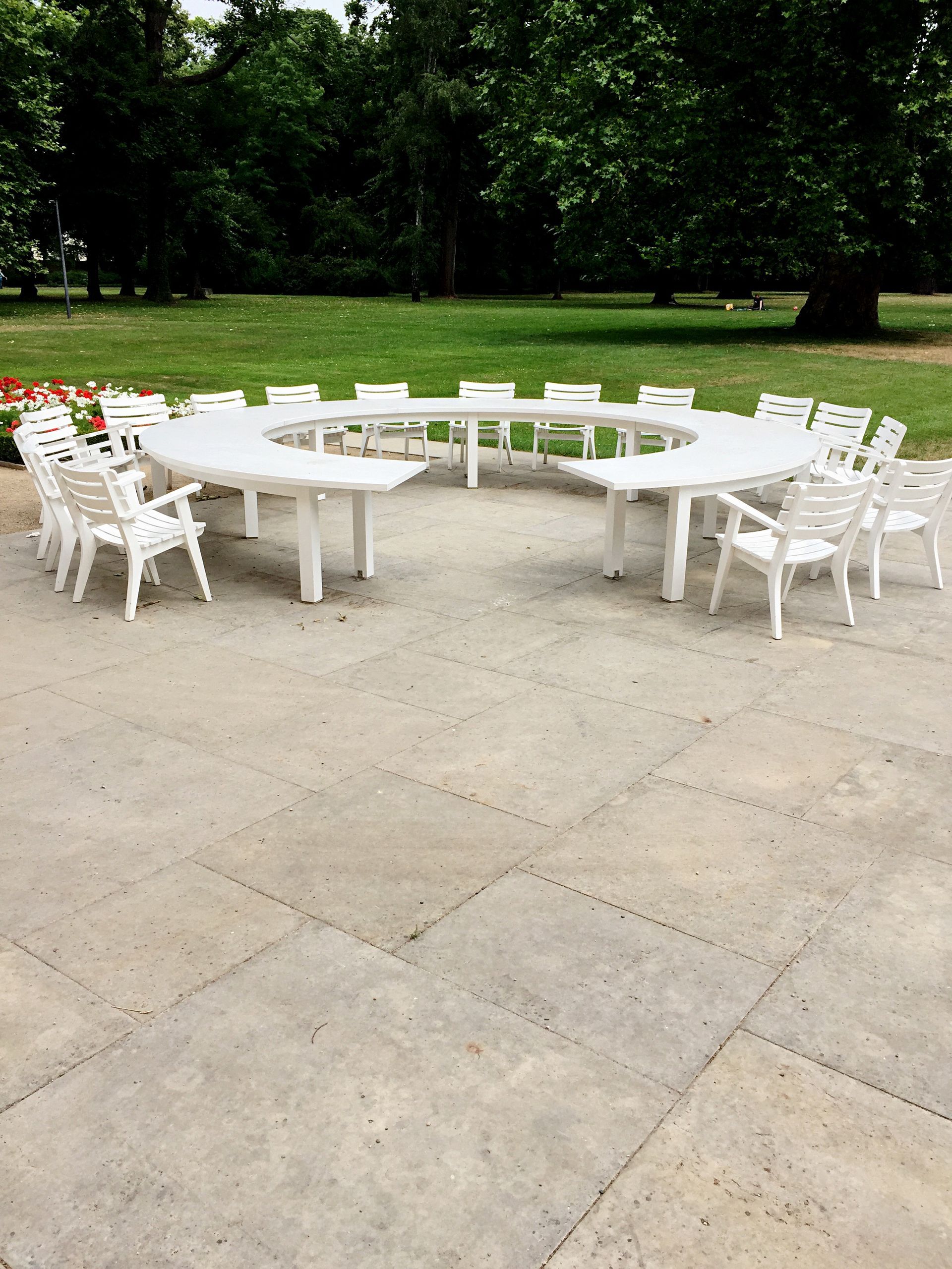 A circle of white tables and chairs in a park