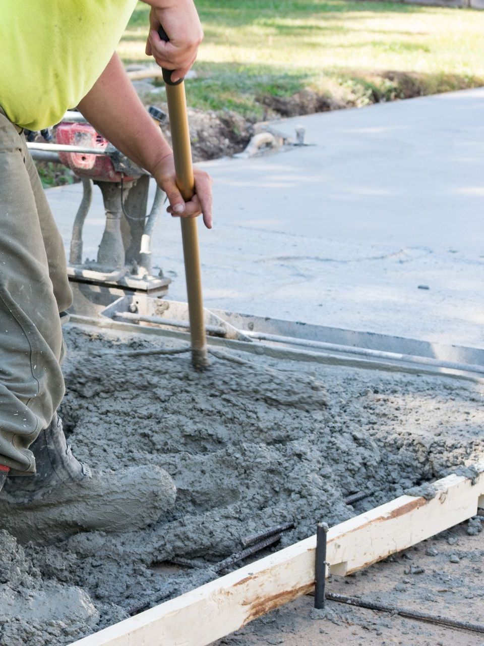 A man is laying concrete on the ground with a shovel.