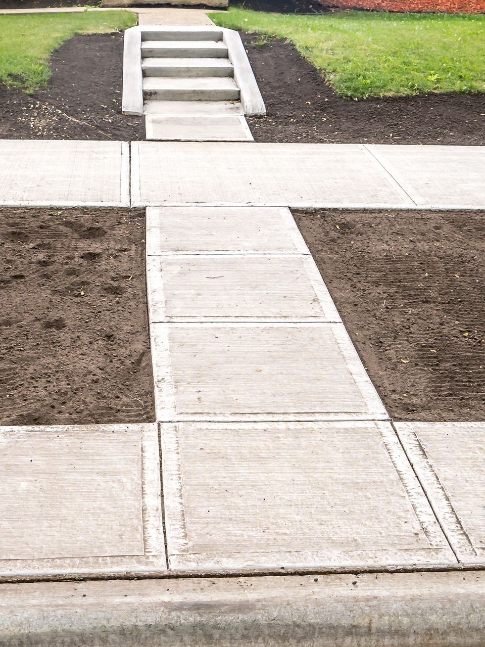 A concrete walkway with steps leading to a grassy area