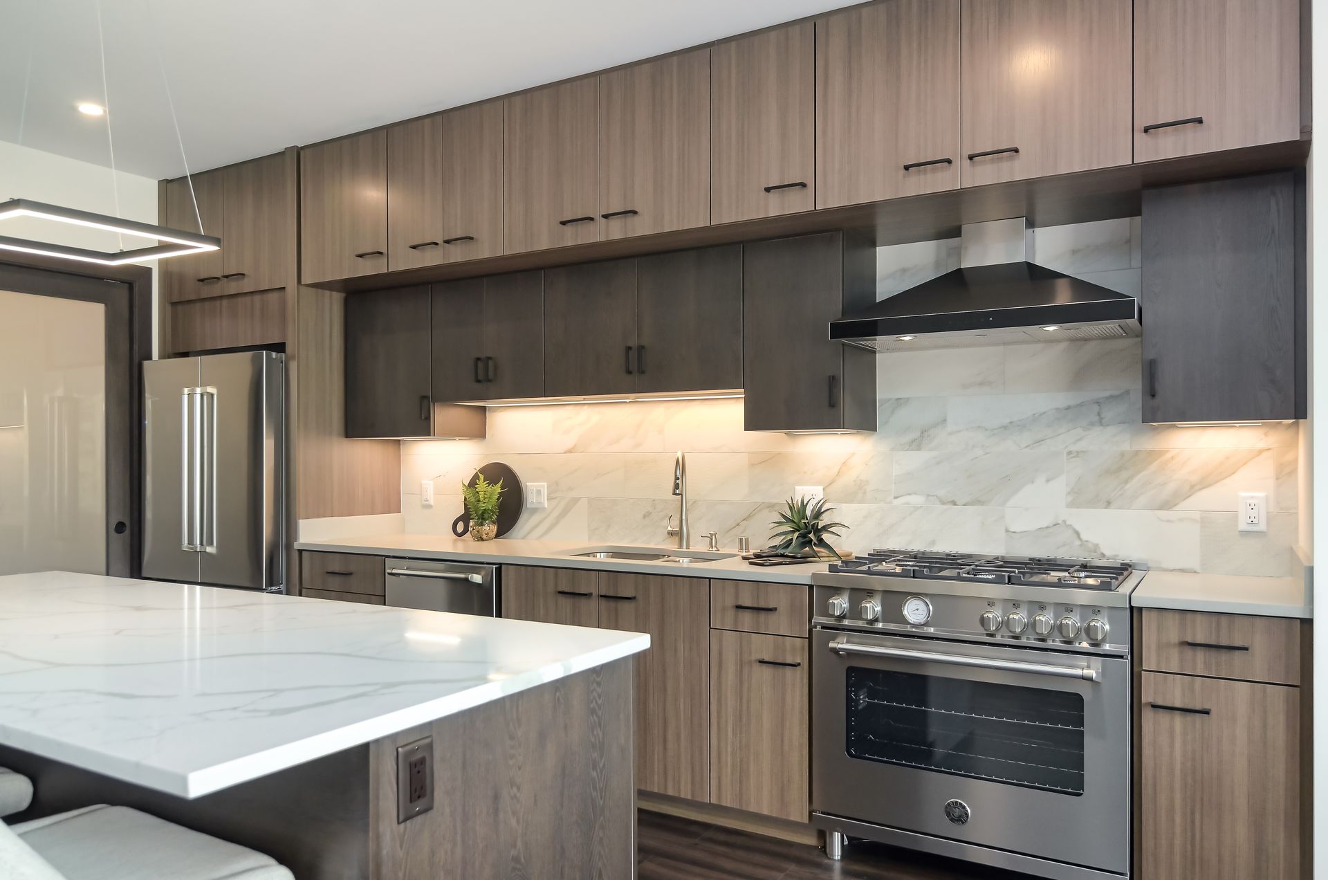Modern kitchen with wood cabinets, marble countertops, stainless steel appliances, and a large island at Ventana Apartments in Wayzata, MN.