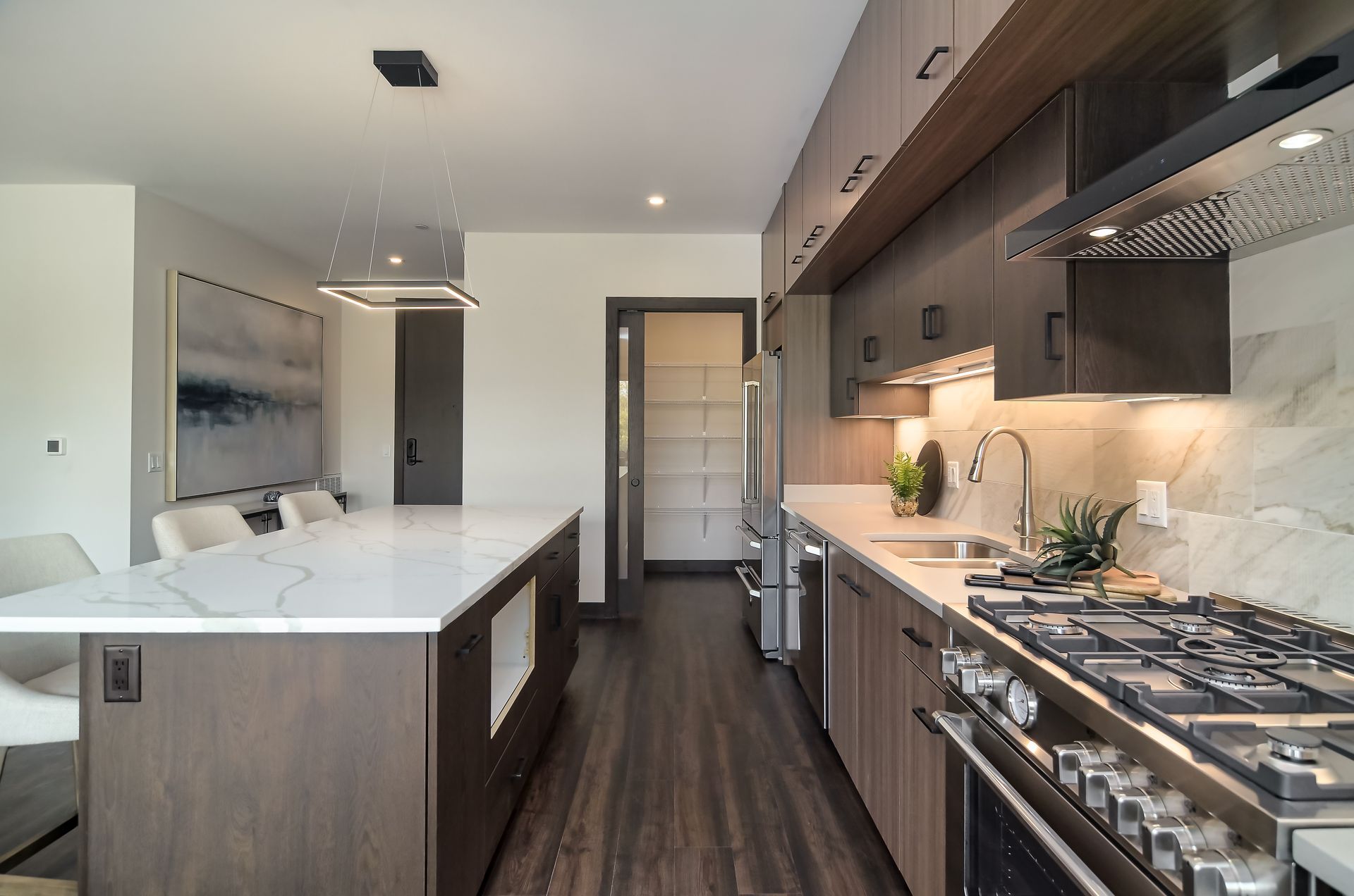 Modern kitchen with island, dark wood cabinets, stainless steel appliances, and a pantry at Ventana Apartments in Wayzata, MN.
