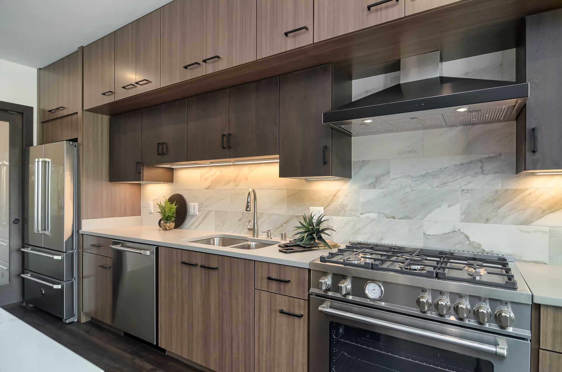 Modern kitchen with stainless steel appliances, dark wood cabinets, and marble backsplash at Ventana Apartments in Wayzata, MN.