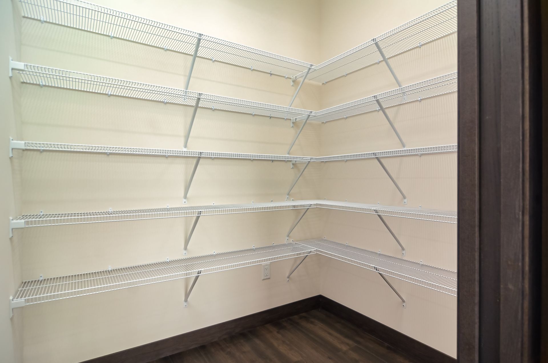 Empty pantry with wire shelving in a corner. Light walls and dark floor at Ventana Apartments in Wayzata, MN.